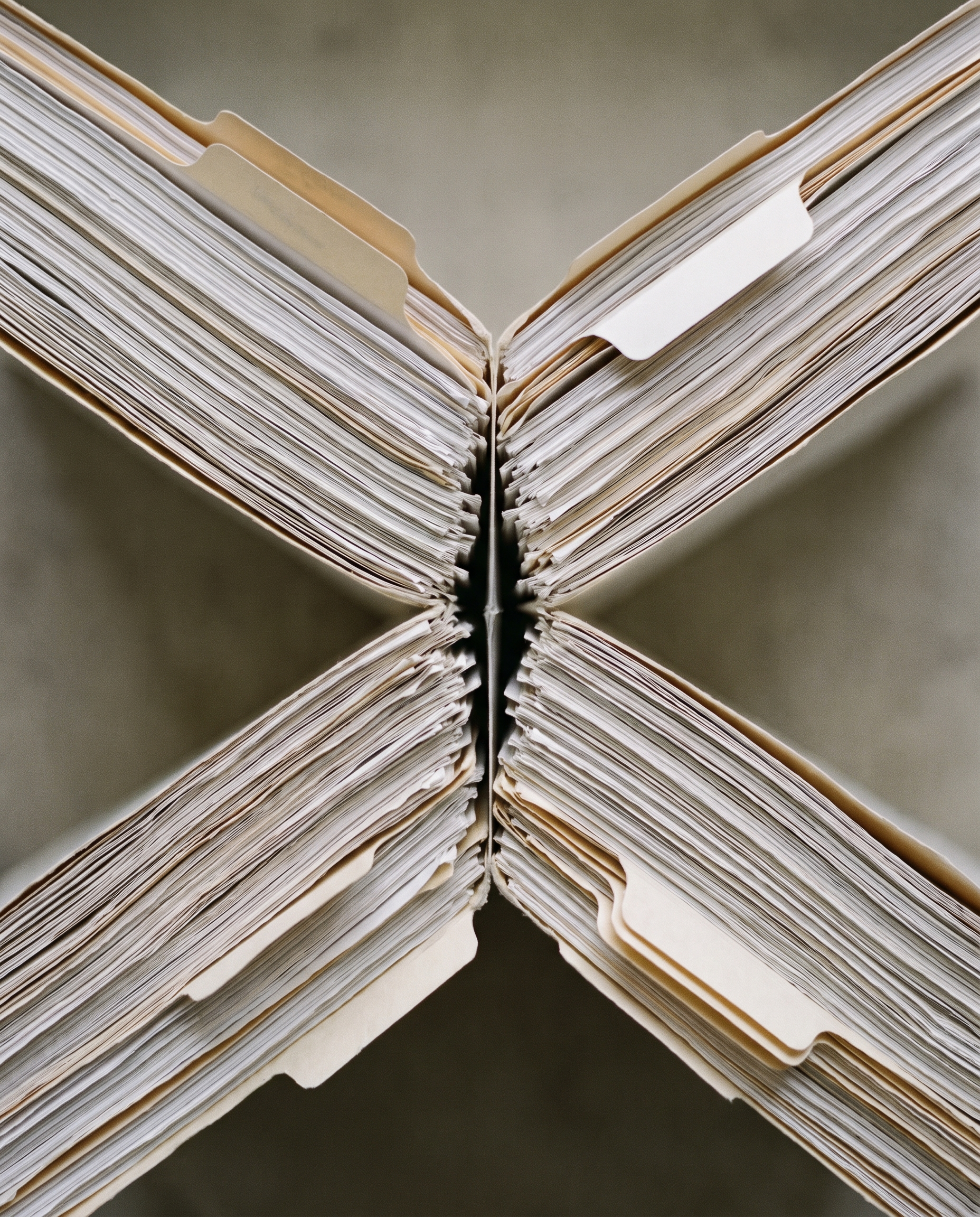 Four bound document rolls converging on a common point, arranged as a single coordinated file — no desk surface and no people or faces are shown.